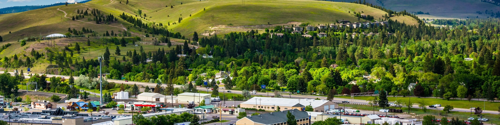 A town nestled by a river with mountains in the background.