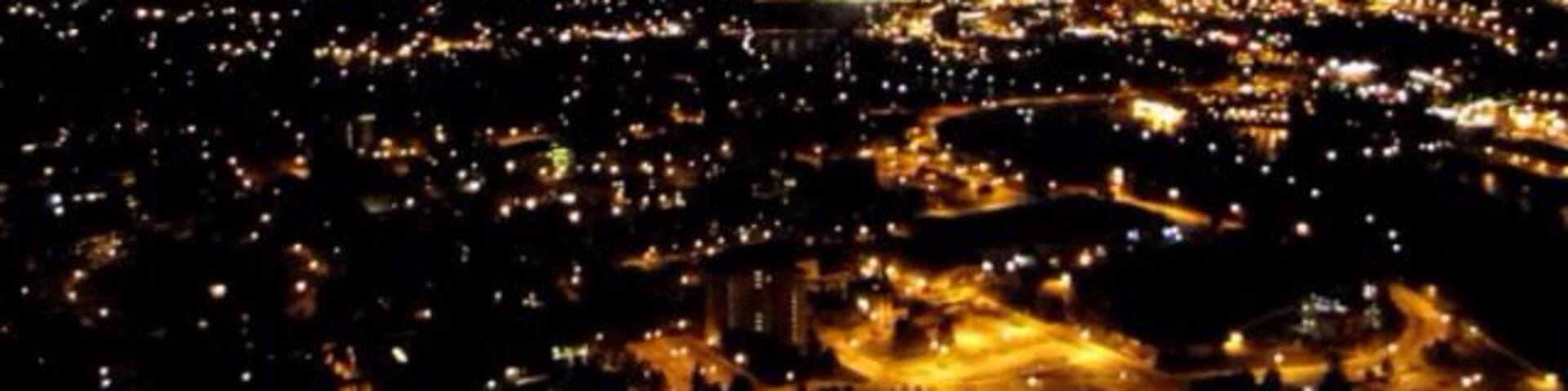 A cityscape at night with illuminated streets and buildings.