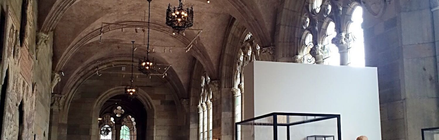Ein Museuminnenraum mit Gewölbedecken, hängenden Kronleuchtern und ausgestellten klassischen Skulpturen.