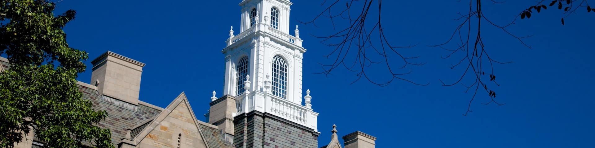 A historic building with a prominent white tower and a golden weather vane.