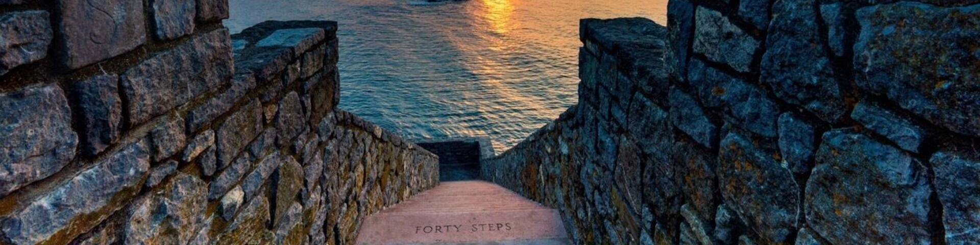 A stone pathway leading to a sunset over water, with the text 'FORTY STEPS' visible on the path.