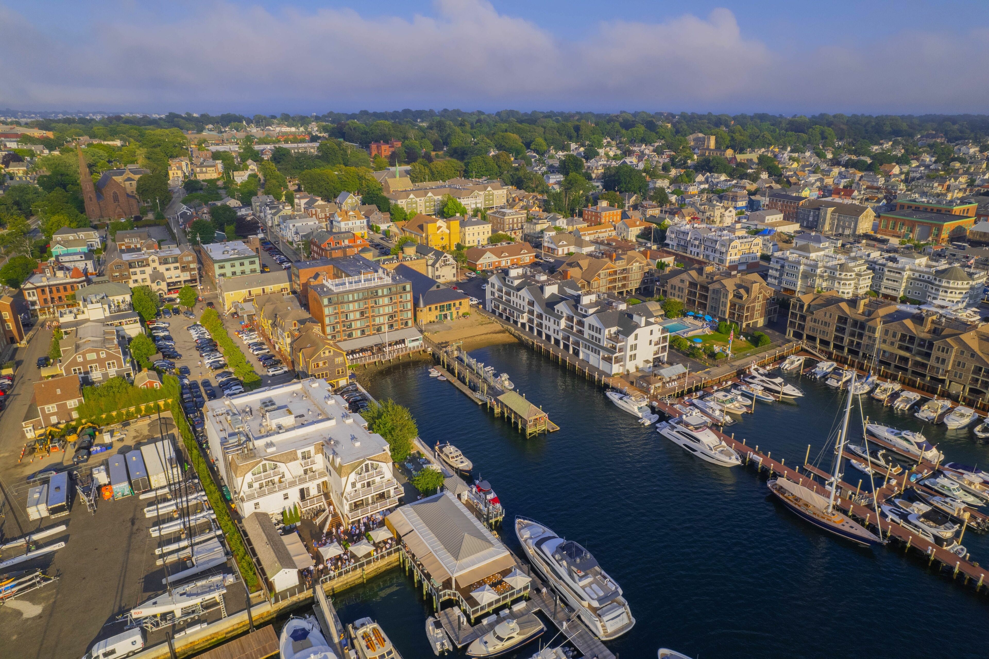 A marina with boats docked, surrounded by a cityscape with historic buildings and a river.