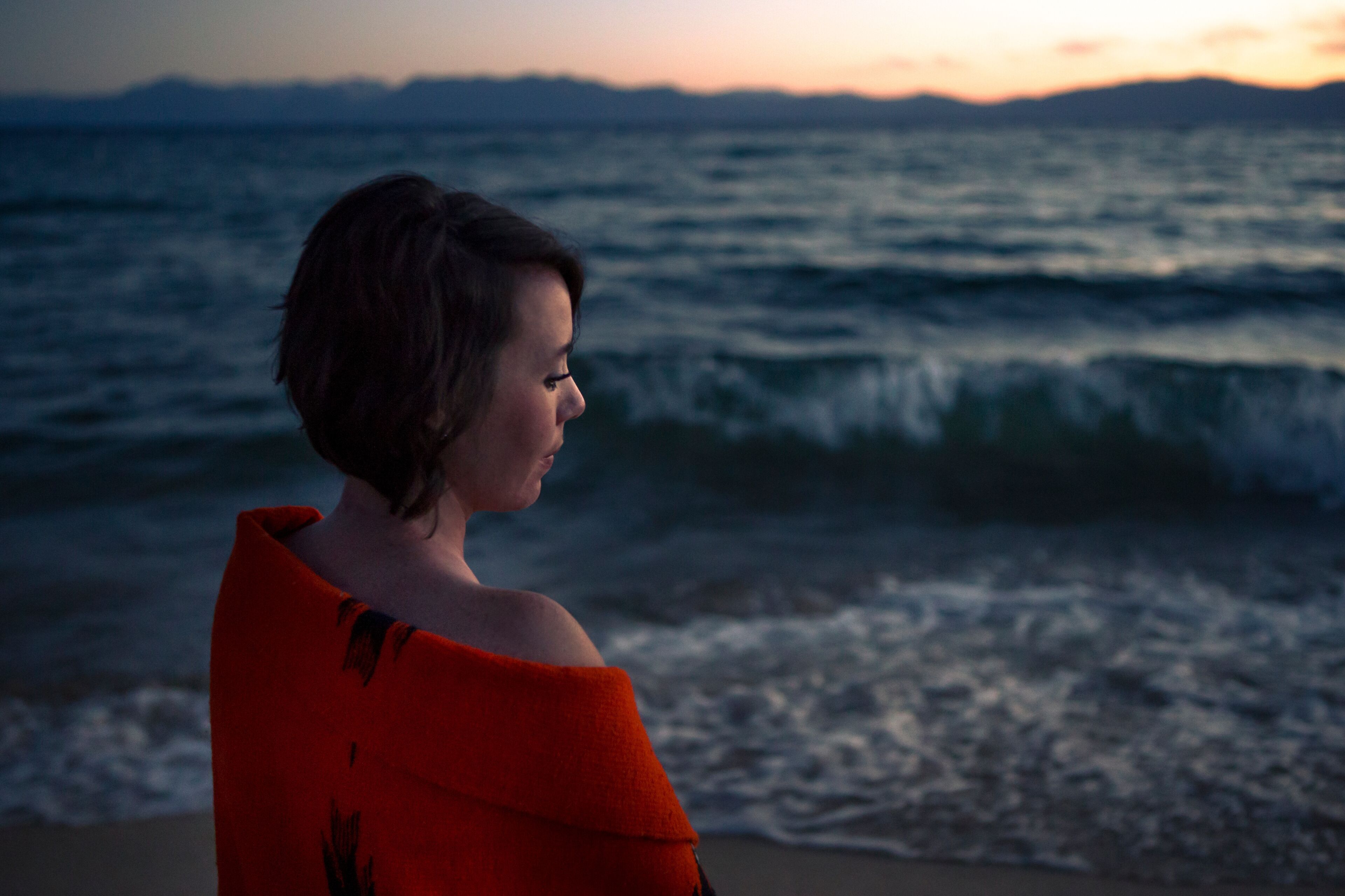 Women contemplates during sunset near mountain lake