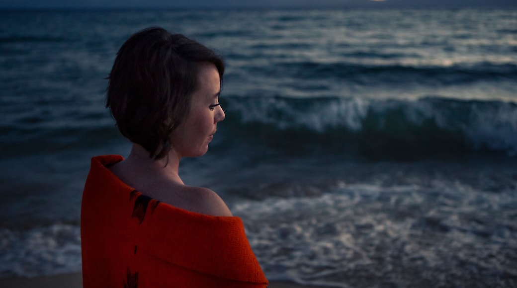 Women contemplates during sunset near mountain lake