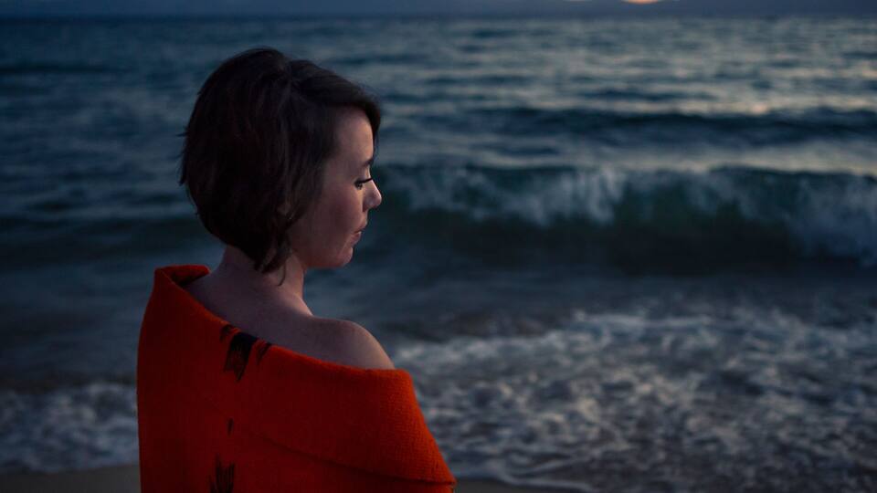 A person standing on a beach with waves in the background.