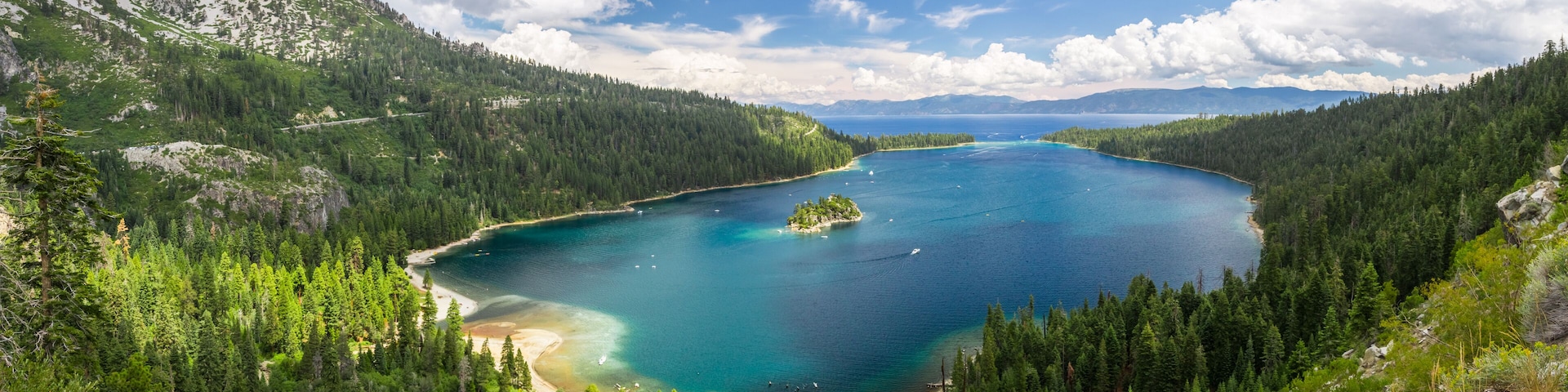 Um lago azul-turquesa cercado por florestas densas e montanhas.