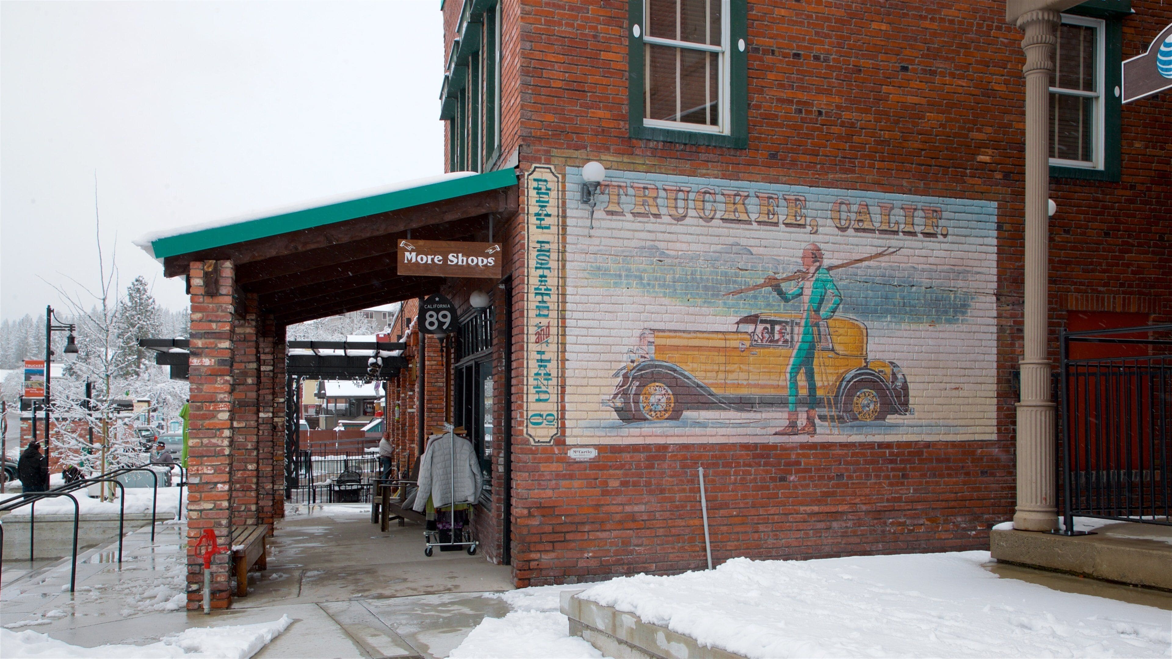A brick building with a mural of a man and a yellow truck.