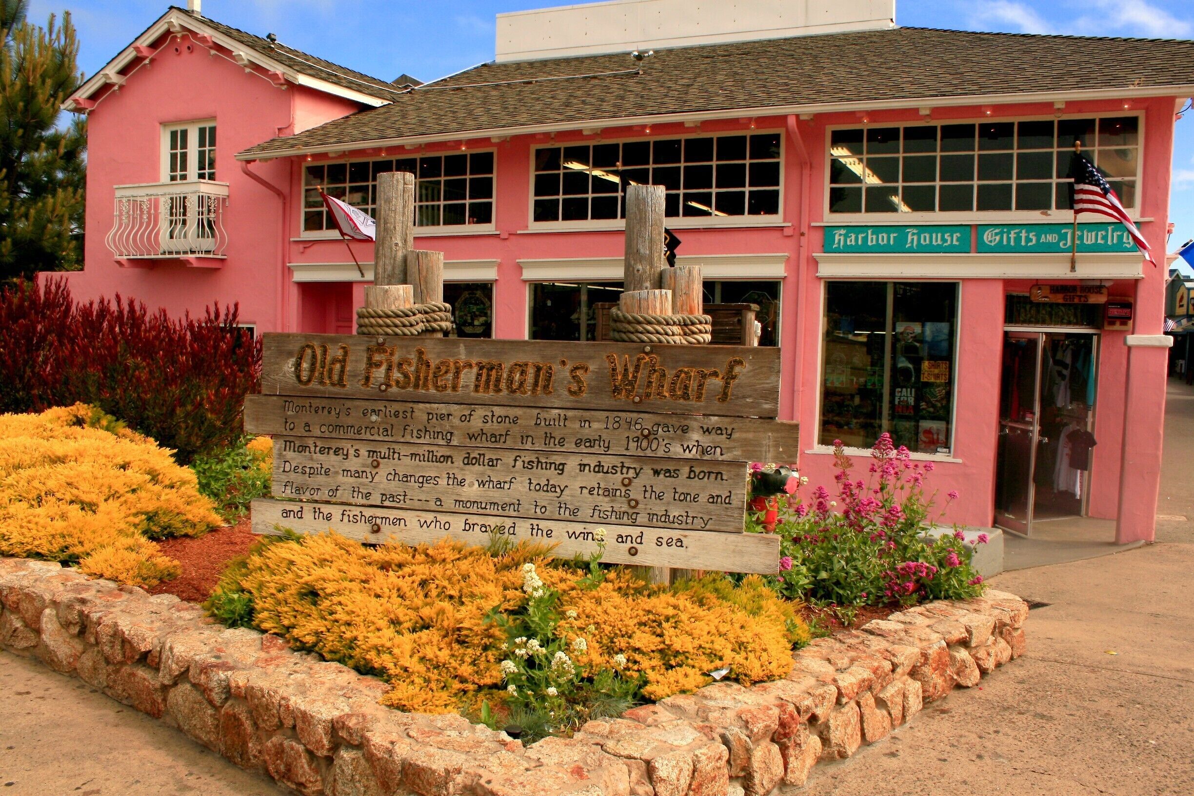 A pink building with a sign reading "Old Fisherman's Wharf" and an American flag.