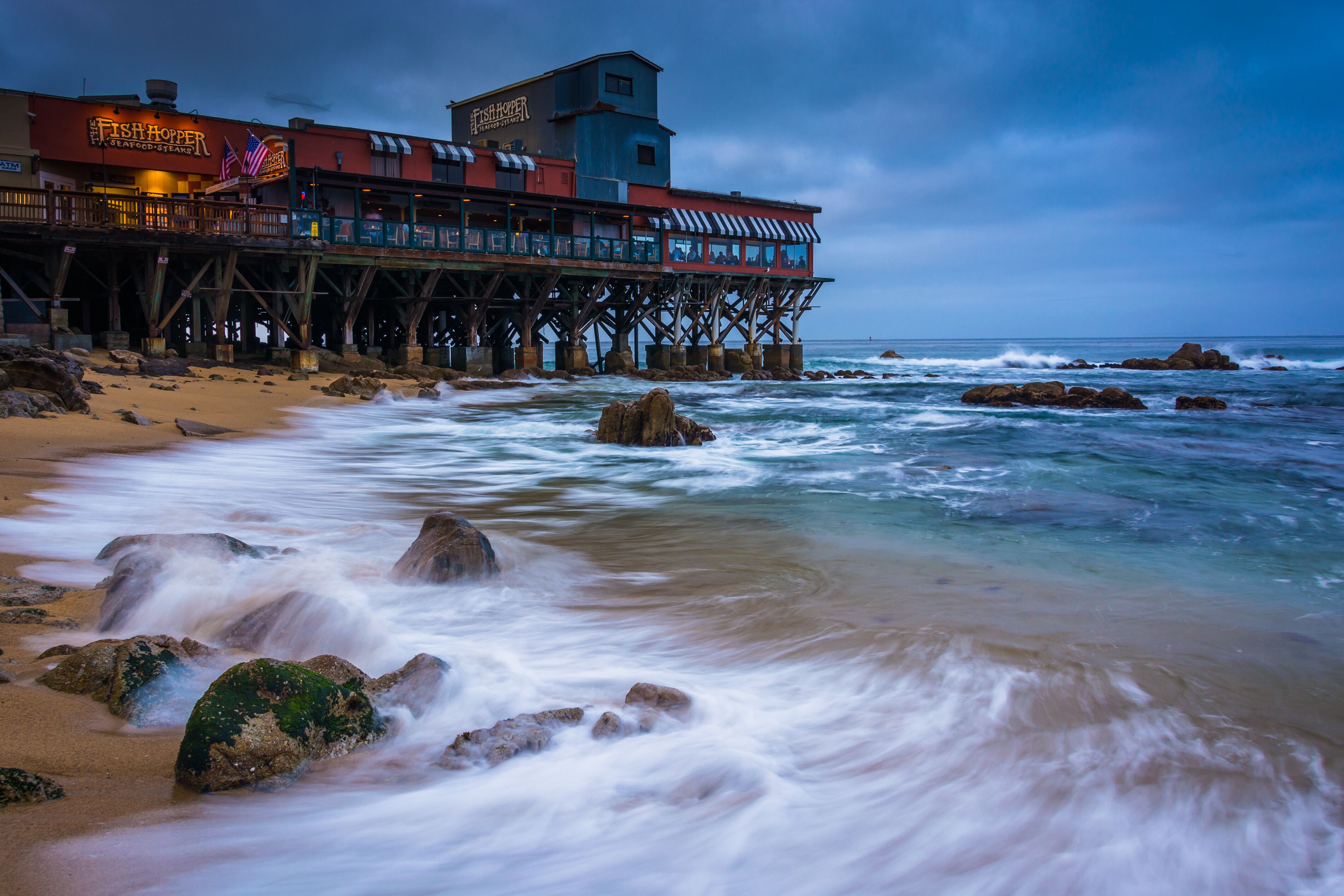 A pier extending into the ocean with a restaurant named 'Fish Hopper' on it.