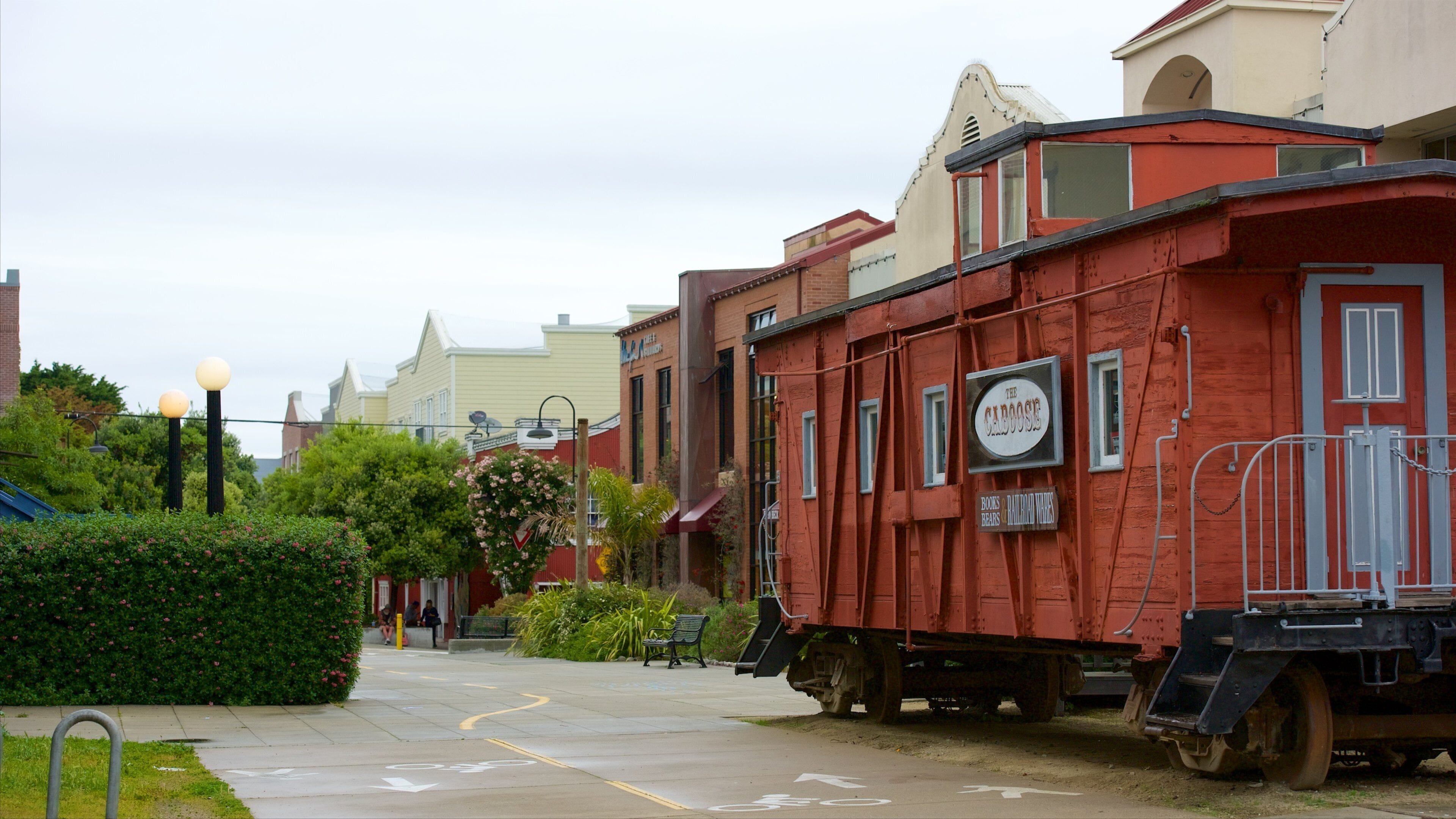 A red caboose with a sign reading "The Caboose" and "Books Bears & Railroad Rides" parked on a street.