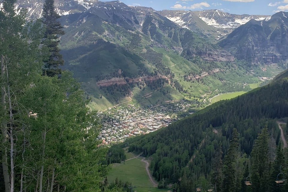 A mountainous landscape with a valley, a town, and a ski lift.