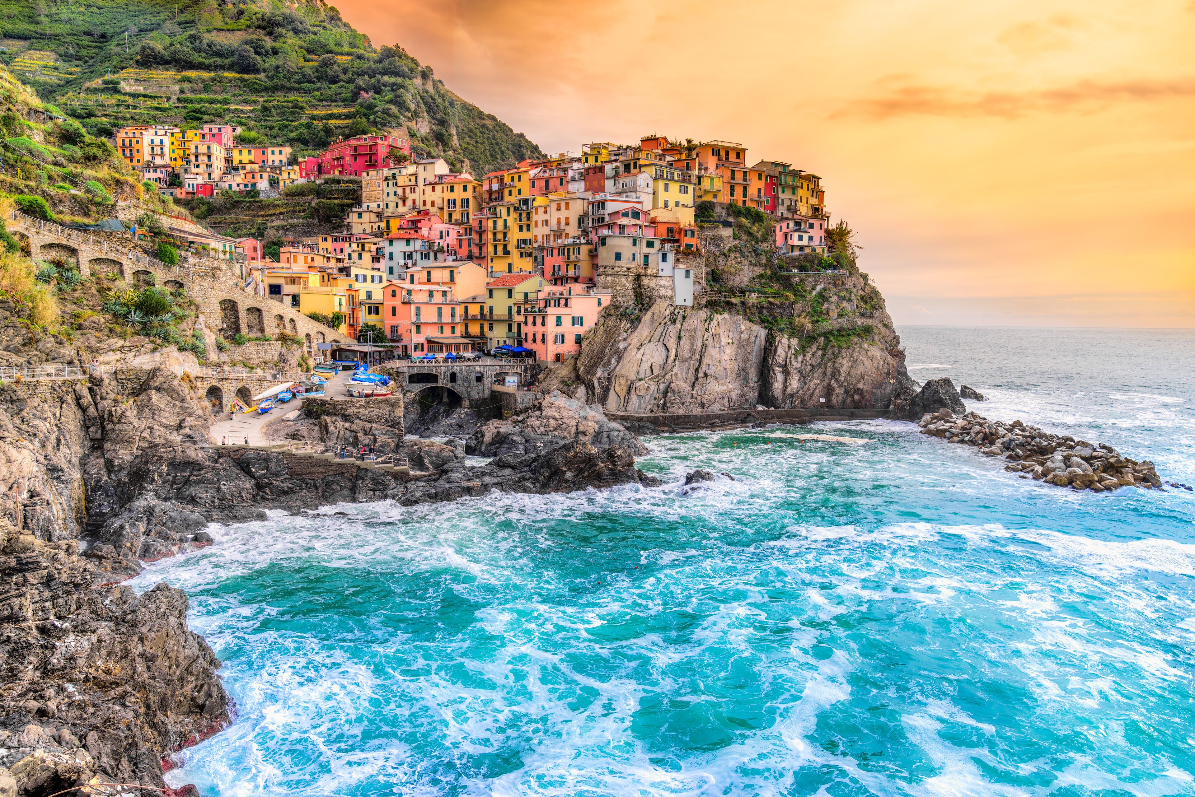 A coastal village with colorful buildings perched on a cliff overlooking turquoise waters.