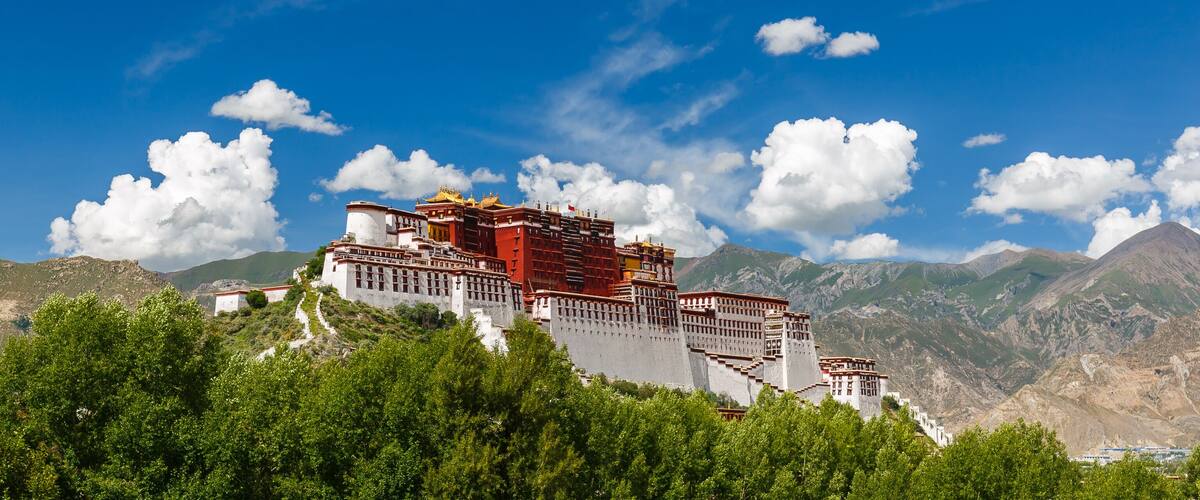 LHASA, TIBET / CHINA - July 31, 2017: Panorama of Potala Palace - home of the Dalai Lama and Unesco World Heritage. Blue sky, clouds. Amazing view of the ancient fortress. Center of Tibetan Buddhism.