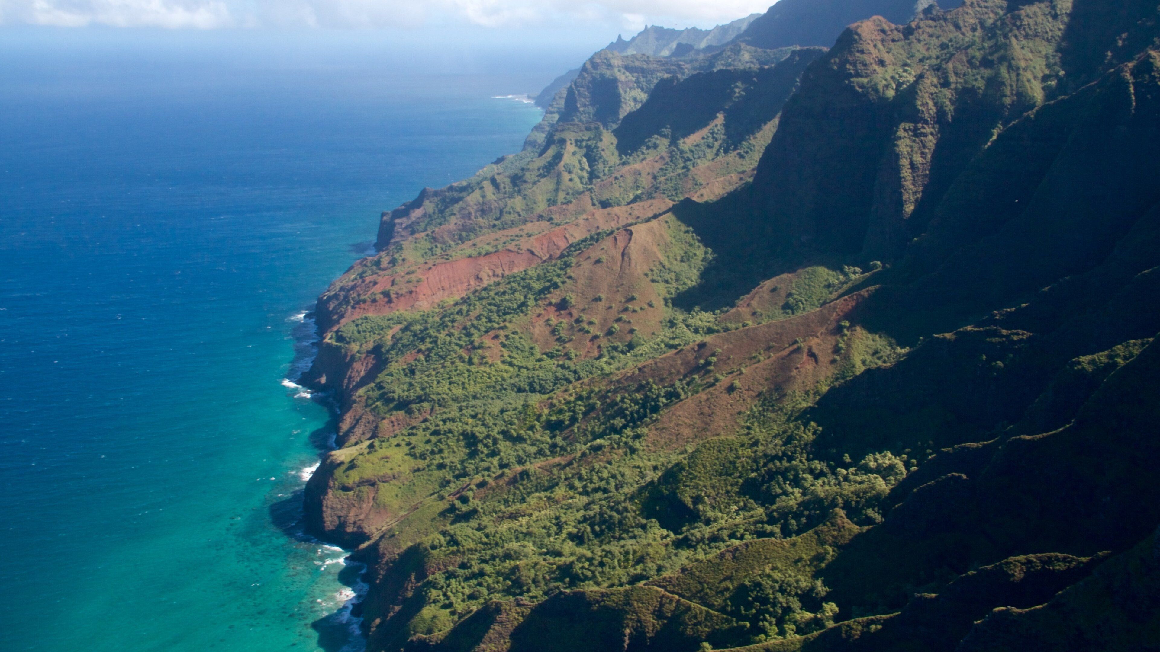 A coastal mountain range with steep cliffs and dense green vegetation.