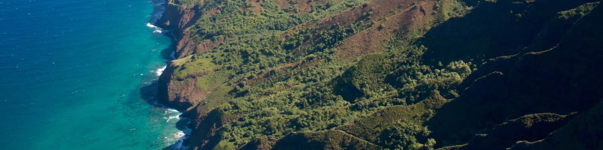 A coastal mountain range with steep cliffs and dense green vegetation.