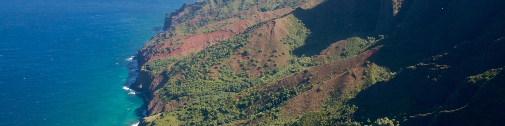 Uma cordilheira costeira com penhascos íngremes e vegetação verde densa.