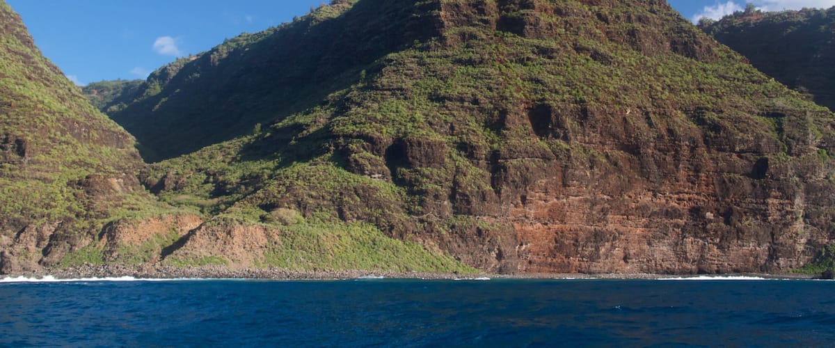 A rugged mountain landscape with lush green vegetation and a clear blue sky.