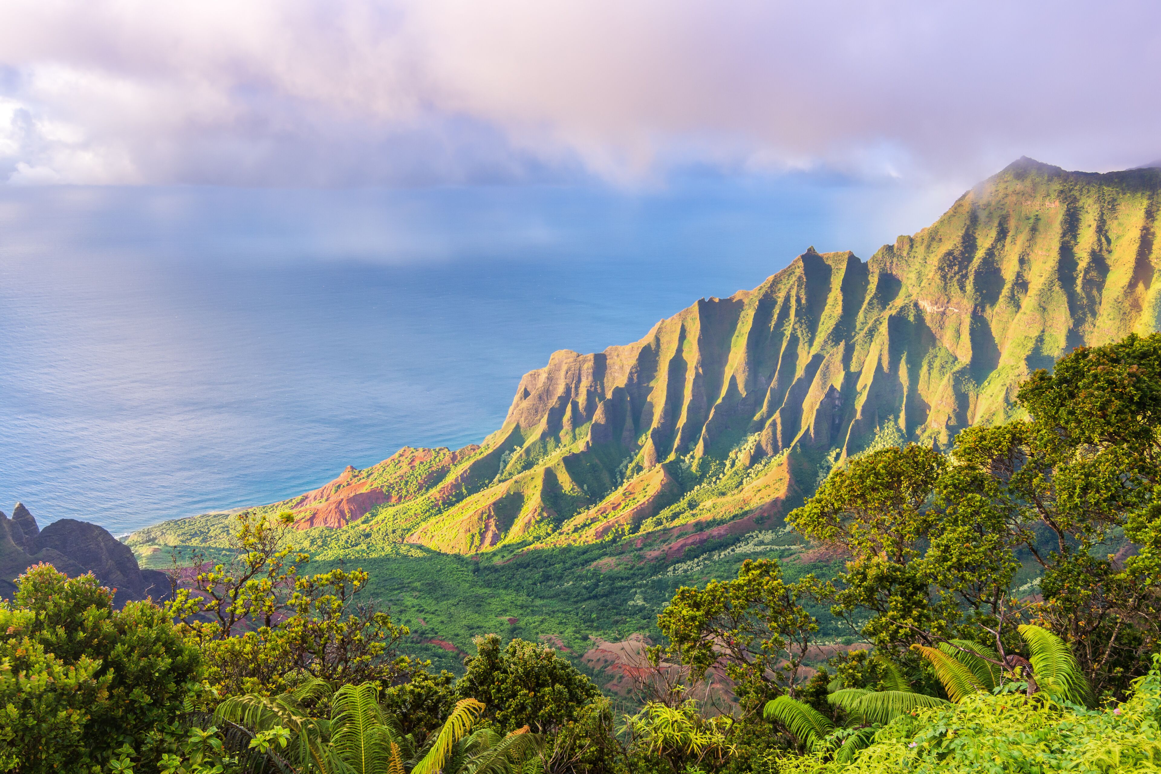 A mountainous landscape with lush greenery and a view of the ocean.