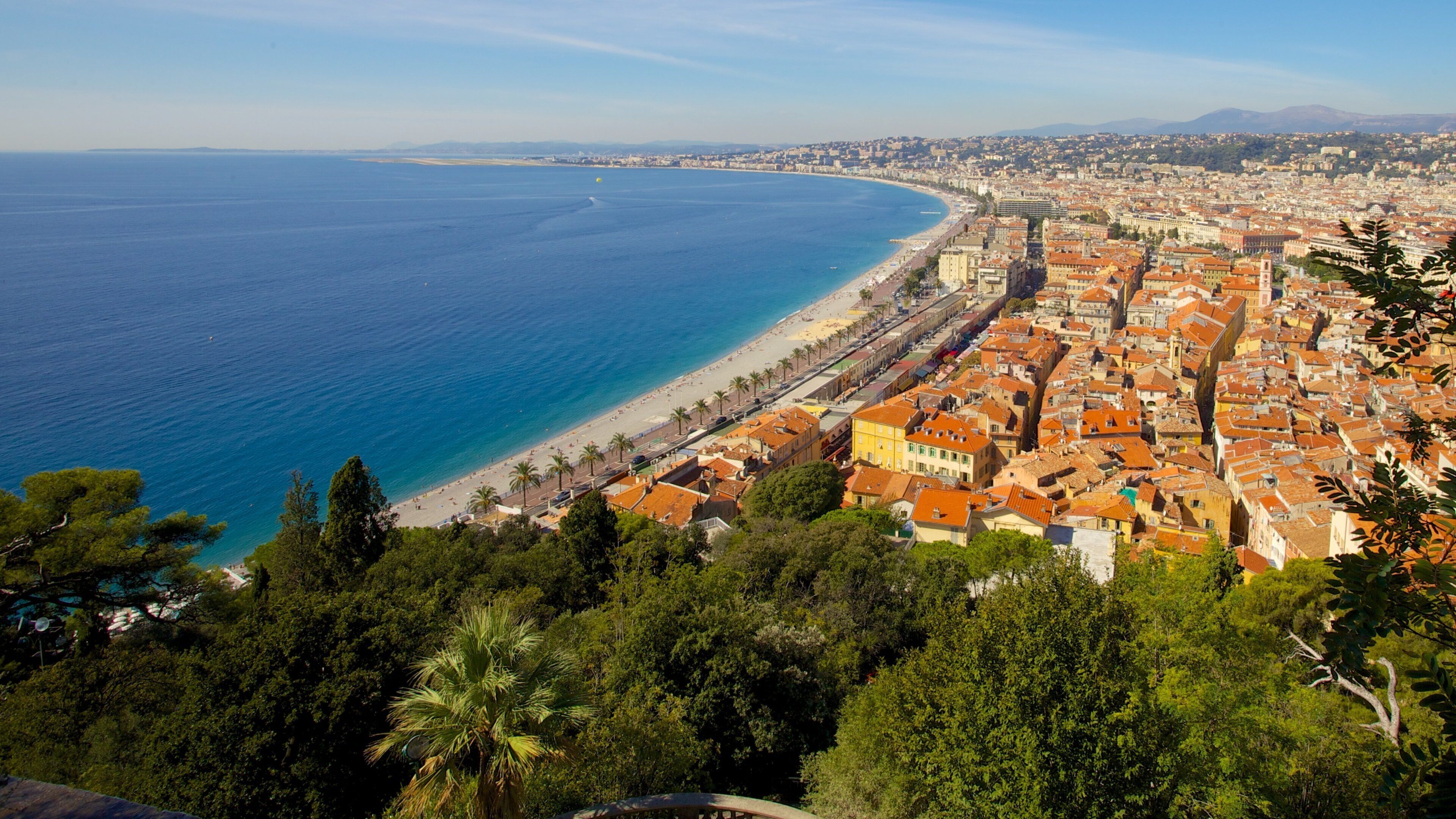 A coastal city with a beach, dense urban area, and surrounding greenery.