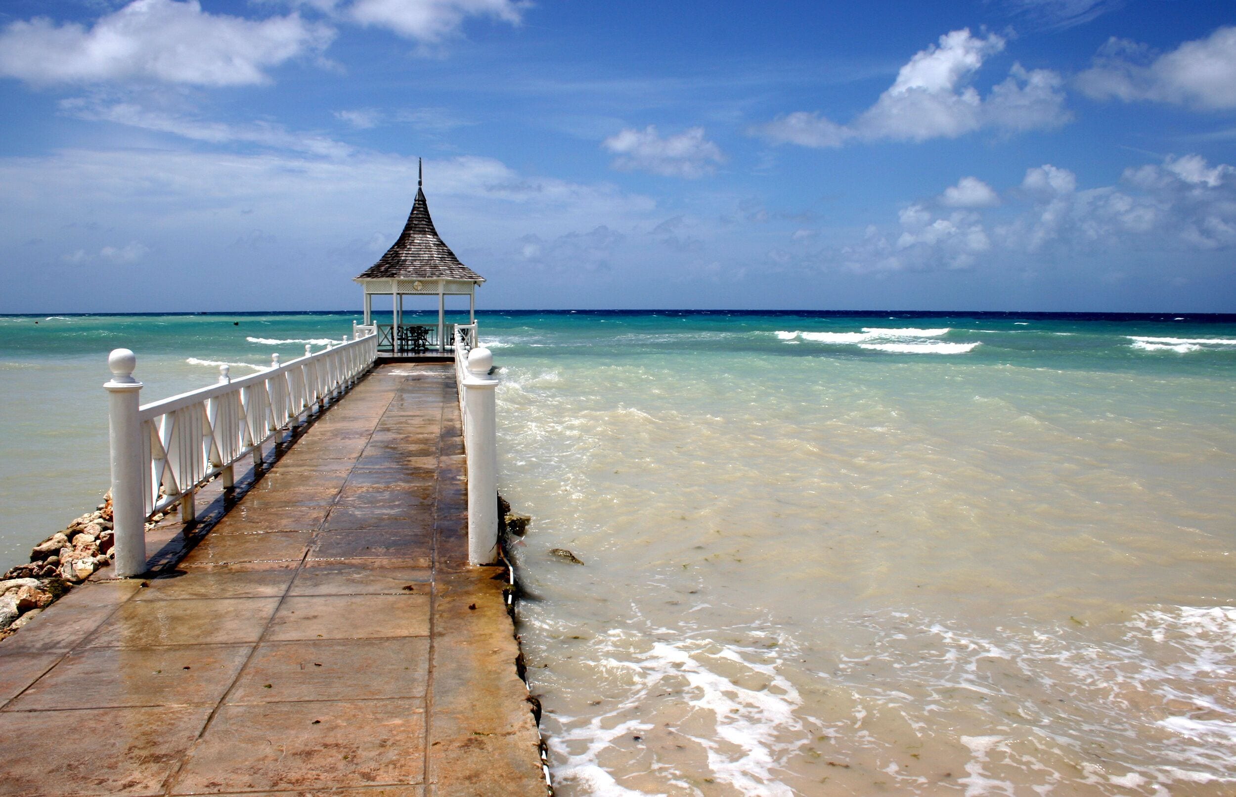 A pier leading to a gazebo by the ocean.