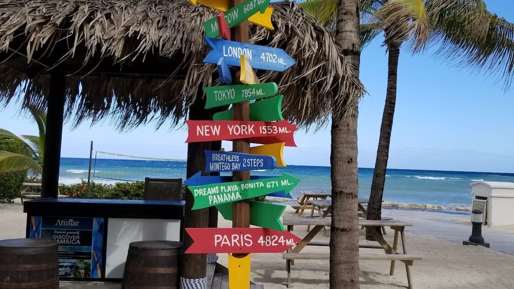 Un panneau indicateur coloré indiquant les directions vers différentes villes et les distances en miles.