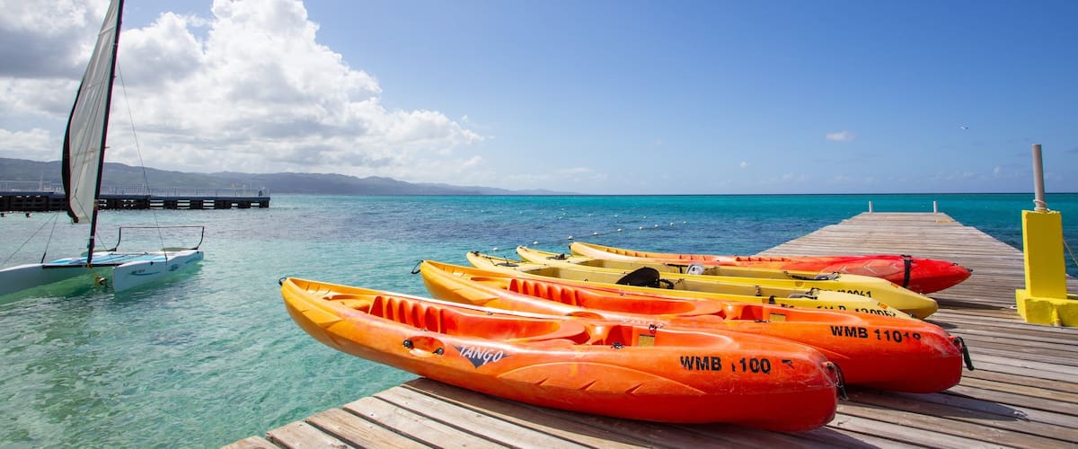 A pier with kayaks and a sailboat.