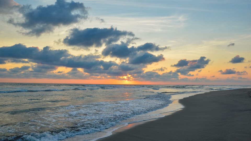 A beach with waves at sunset.