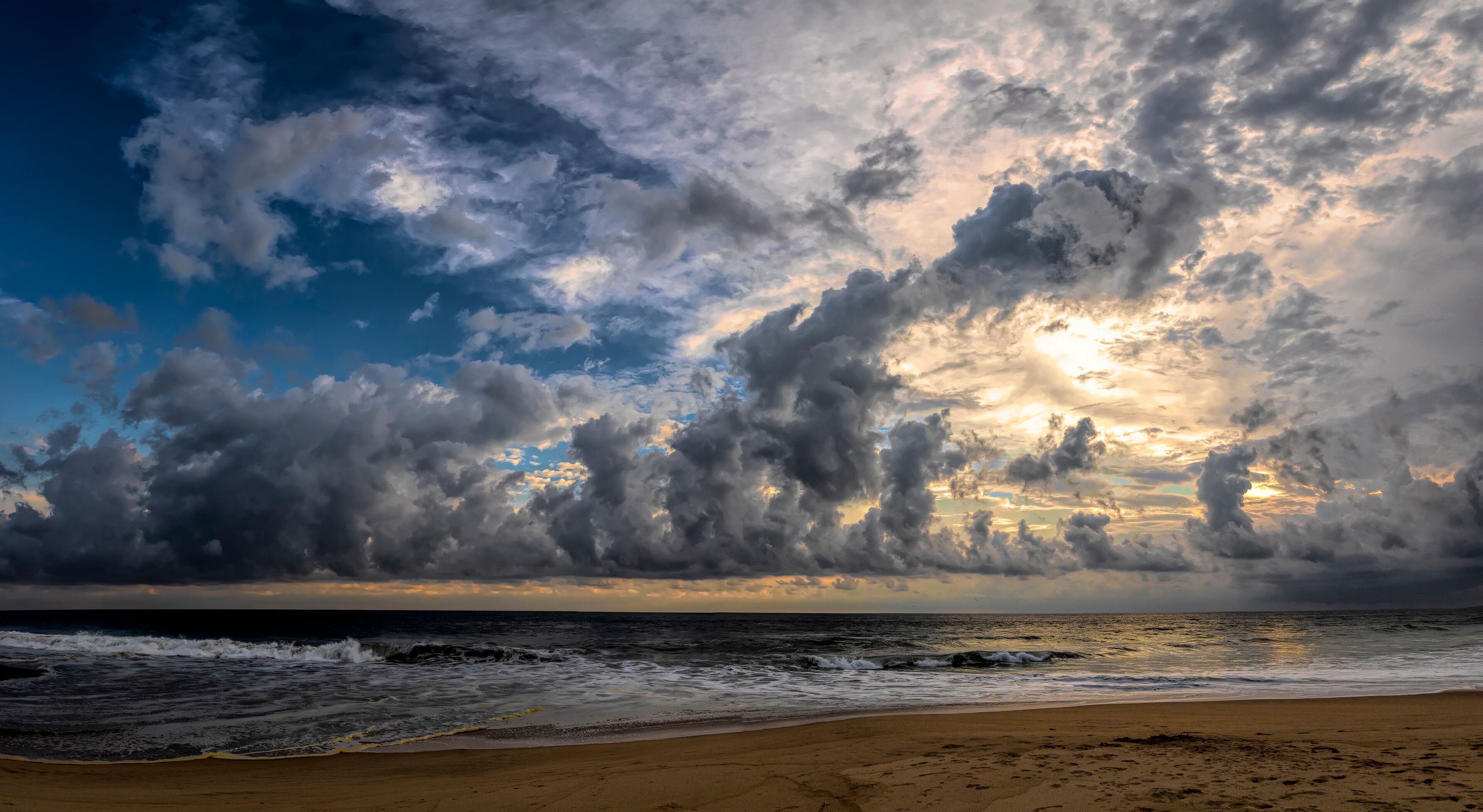 A beach with waves and a cloudy sky.