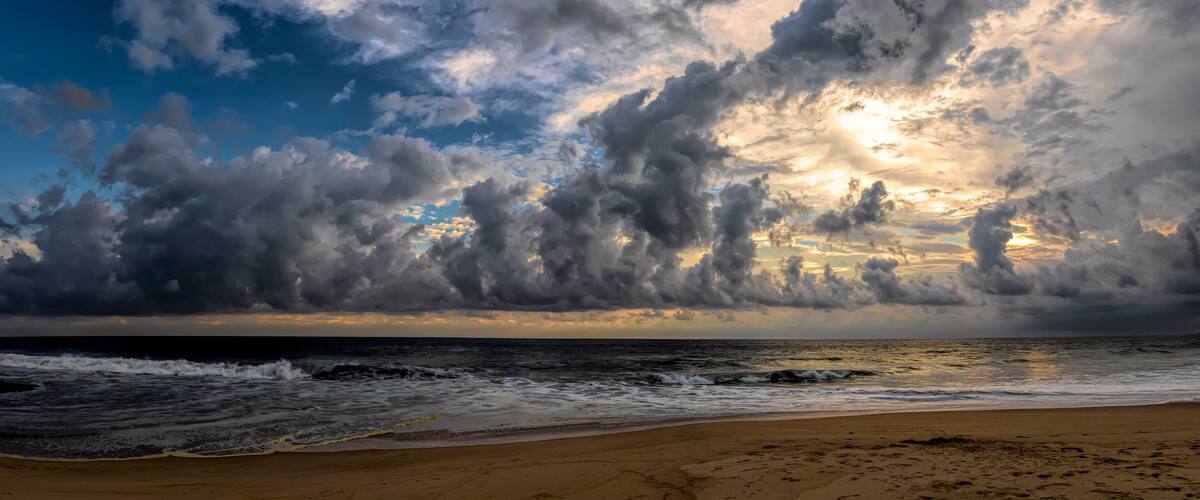 A beach with waves and a cloudy sky.