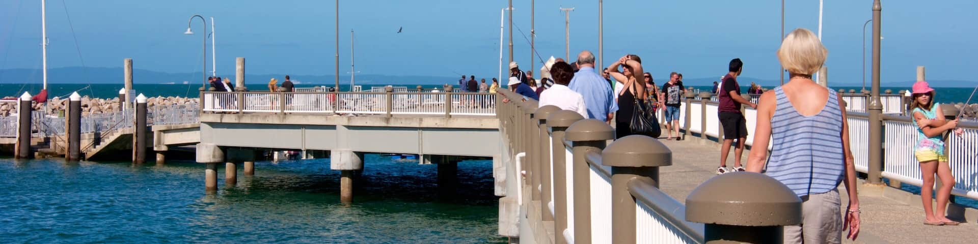 A pier with people walking along it, overlooking the water.