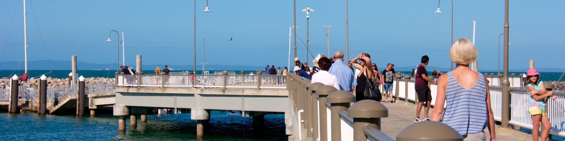 Un muelle con gente caminando, con vistas al agua.