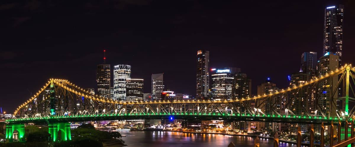 Panoramic view of Story bridge in yellow and green light at nigh time in Brisbane Australia