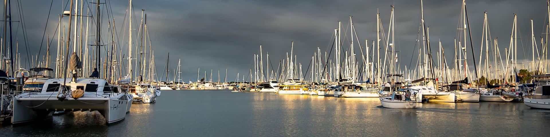 A marina filled with numerous sailboats under a cloudy sky.