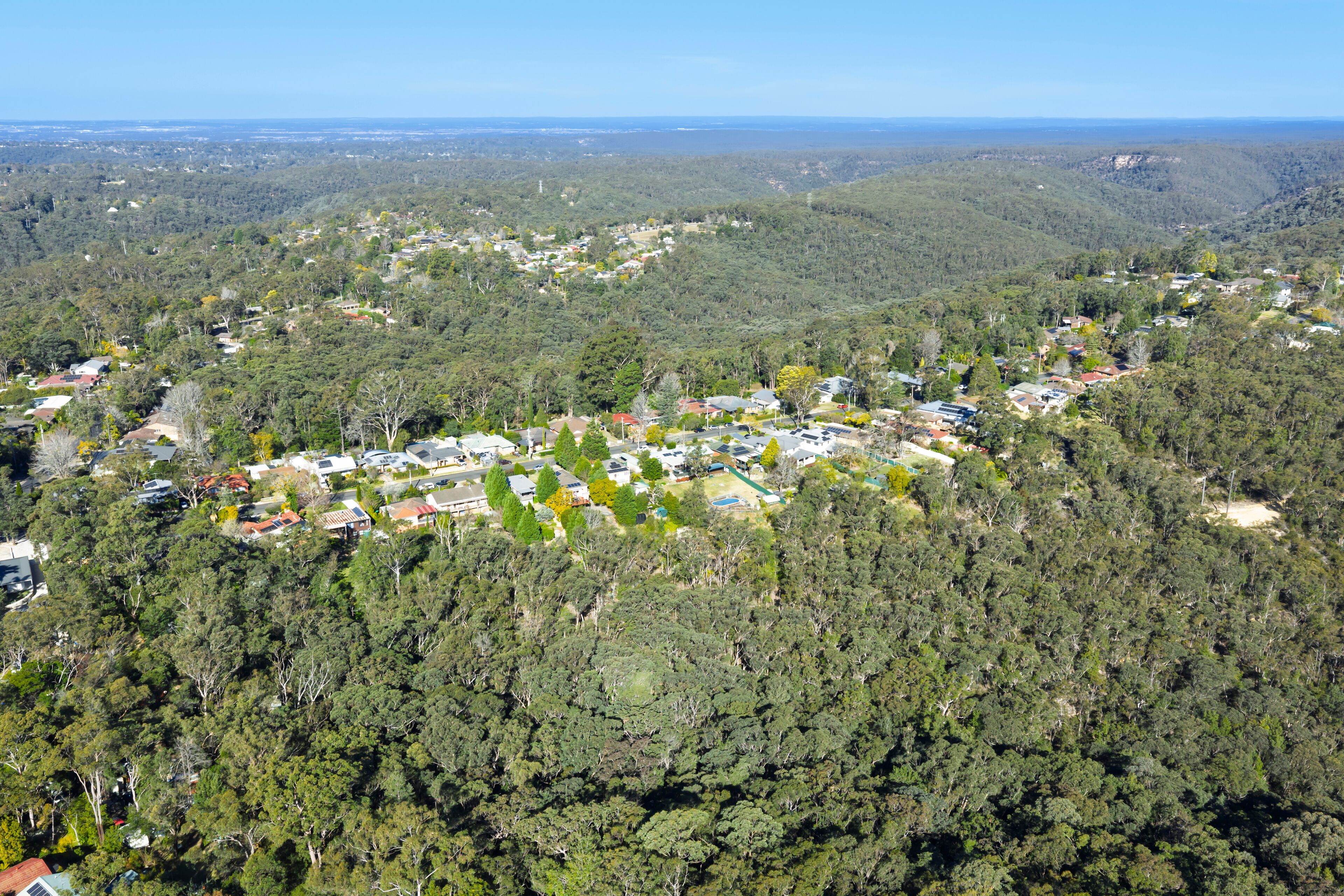 Drone aerial photograph of a precinct of residential houses located amongst trees and lush natural foliage in the town of Springwood in the Blue Mountains, NSW, Australia.