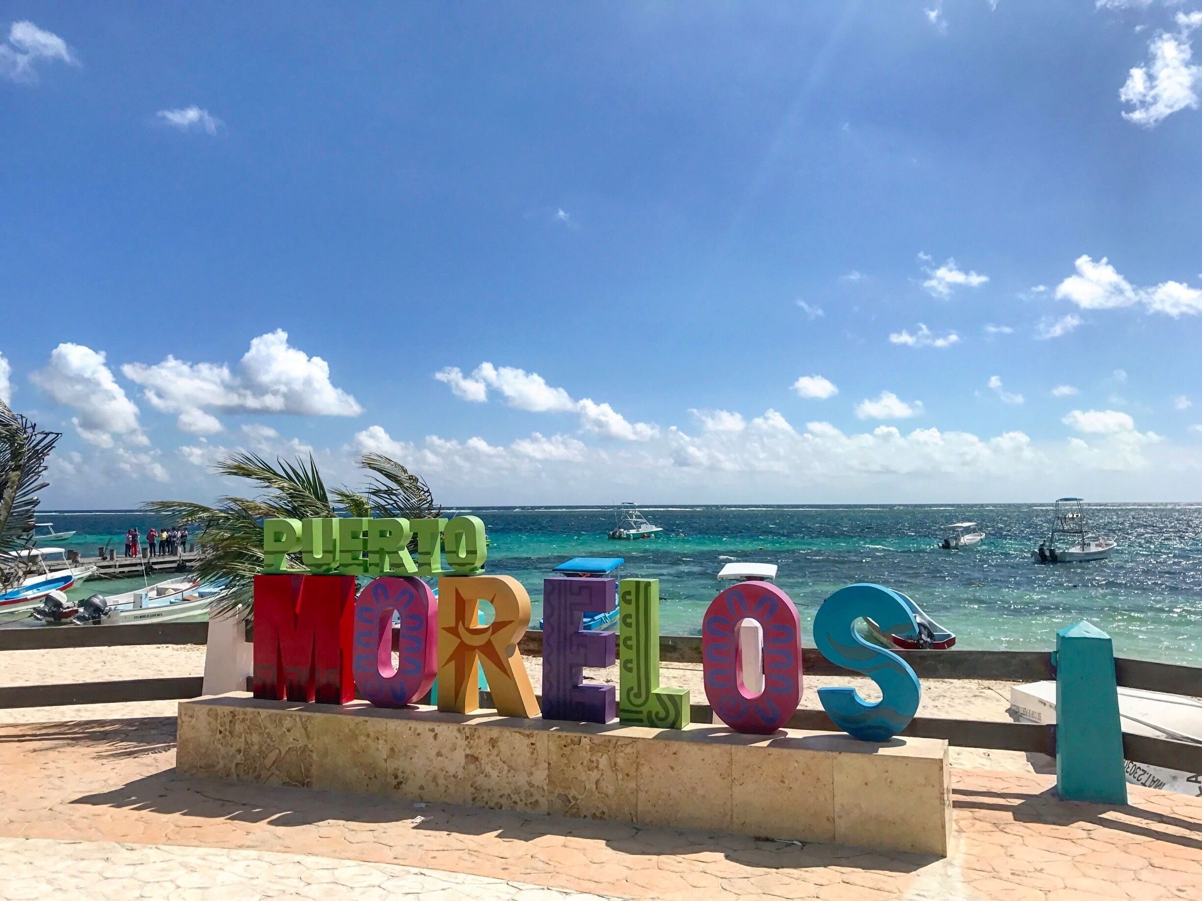 A beach with the sign 'Puerto Morelos' and boats in the water.