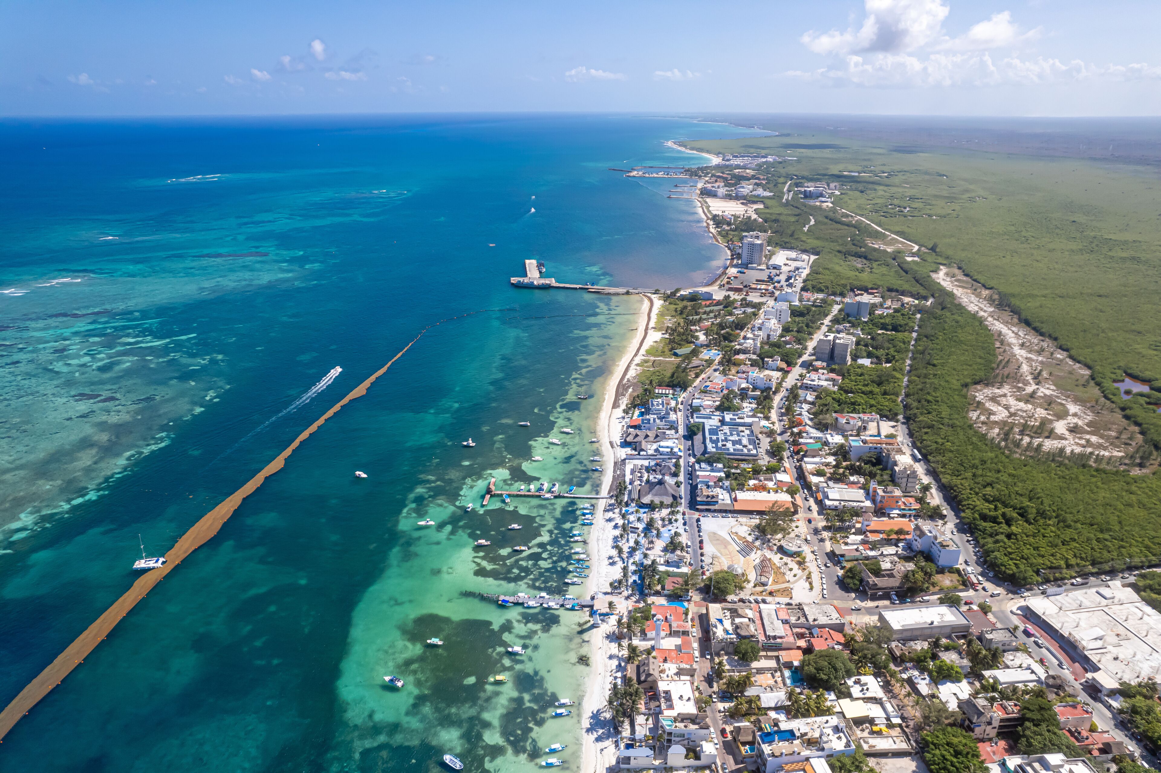 A coastal city with a beach, a pier, and a clear blue sea.
