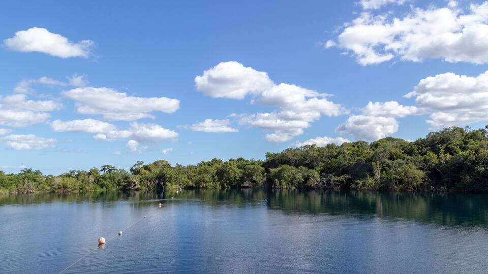 A calm lake with a clear sky and scattered clouds.
