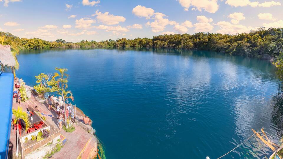 A calm lake with a dock and people relaxing.