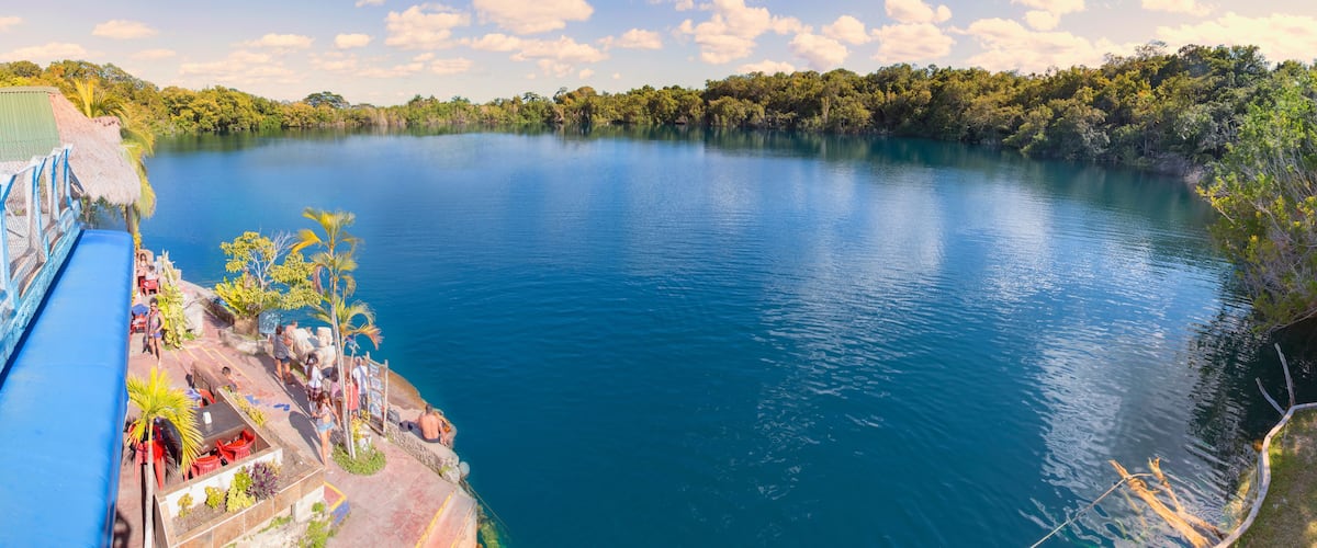 A calm lake with a dock and people relaxing.