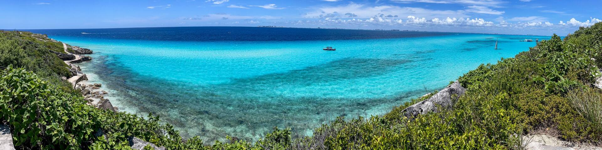 A turquoise sea, clear skies, and lush greenery.