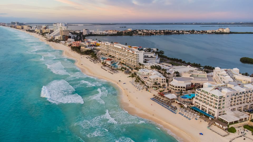 A coastal cityscape with a beach, ocean, and a Ferris wheel.