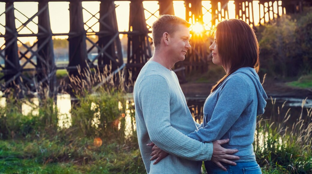 A mid adult couple standing face to face and gazing at one another in a park in autumn; St. Albert, Alberta, Canada