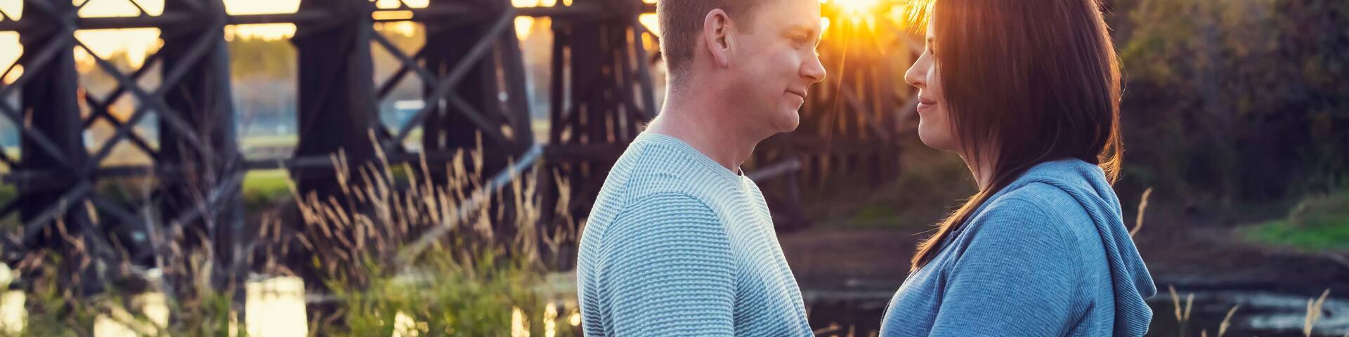 A mid adult couple standing face to face and gazing at one another in a park in autumn; St. Albert, Alberta, Canada