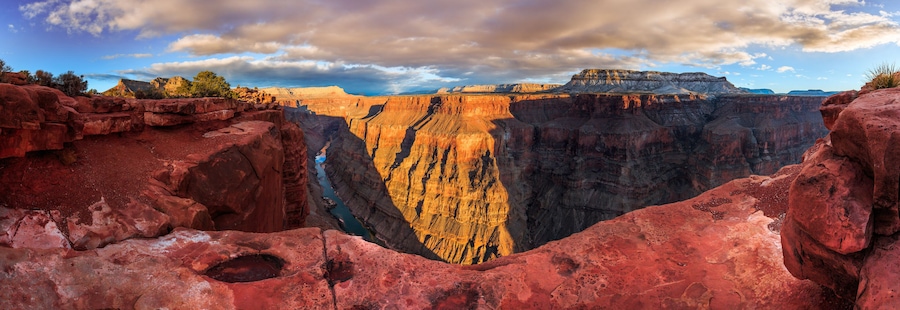Un canyon profond, avec des formations rocheuses rouges et une rivière qui le traverse.