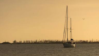 Un voilier sur une eau calme, au coucher du soleil.