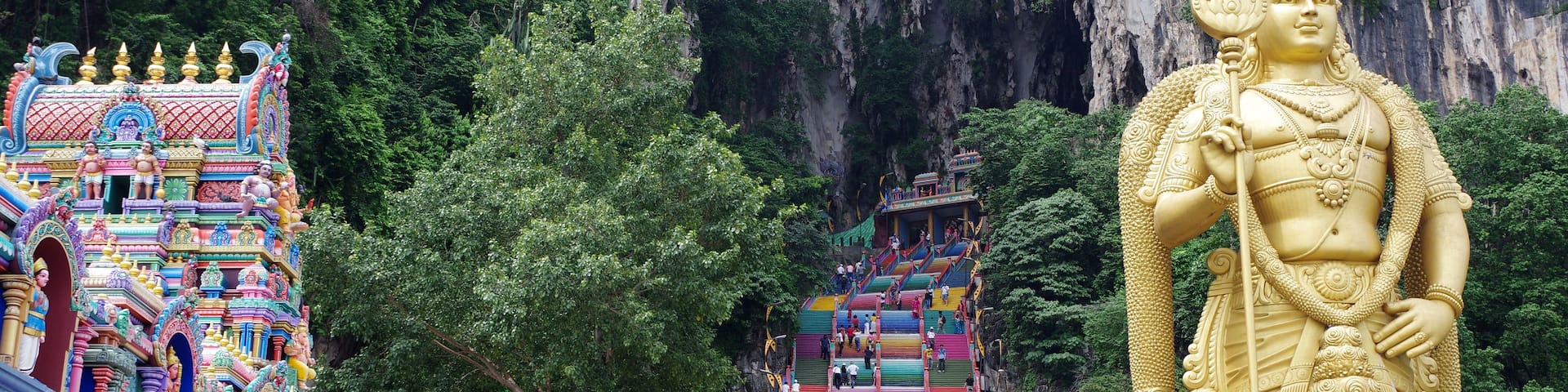 A large golden statue, colorful temple architecture, and a staircase leading up to the temple.