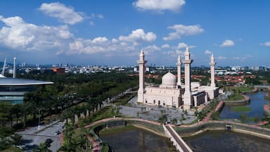 Una mezquita con tres minaretes, rodeada por un estanque y palmeras.