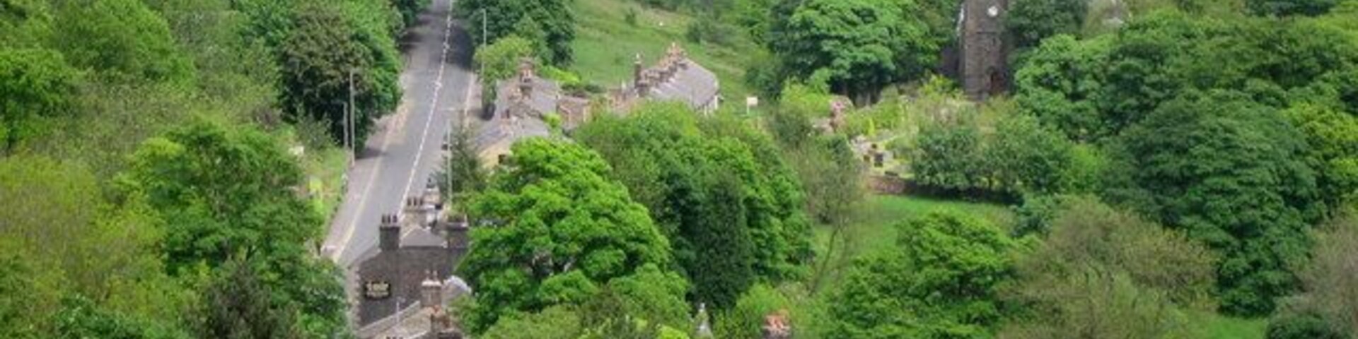 Holcombe Village. The village of Holcombe is in the middle of all the trees with 330268 on the right. The village occupies a picturesque position on the slopes of Holcombe Hill. The buildings in the area are predominantly made up of stone cottages a public house, a restaurant, church and primary school. At one time the village also boasted a shop, post office, and a regular bus service linking it to Holcombe Brook, a neighbouring village in the valley bottom one mile to the south. The main road to the left is Helmshore Road with the sign on wall of 444148 in the foreground.