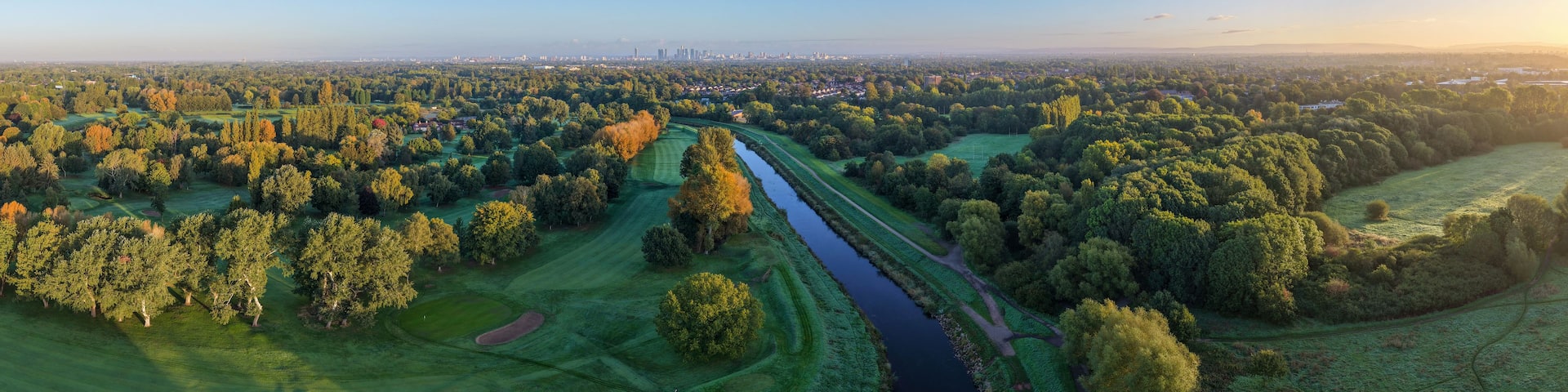 A river meandering through a lush landscape with golf courses and dense forests.