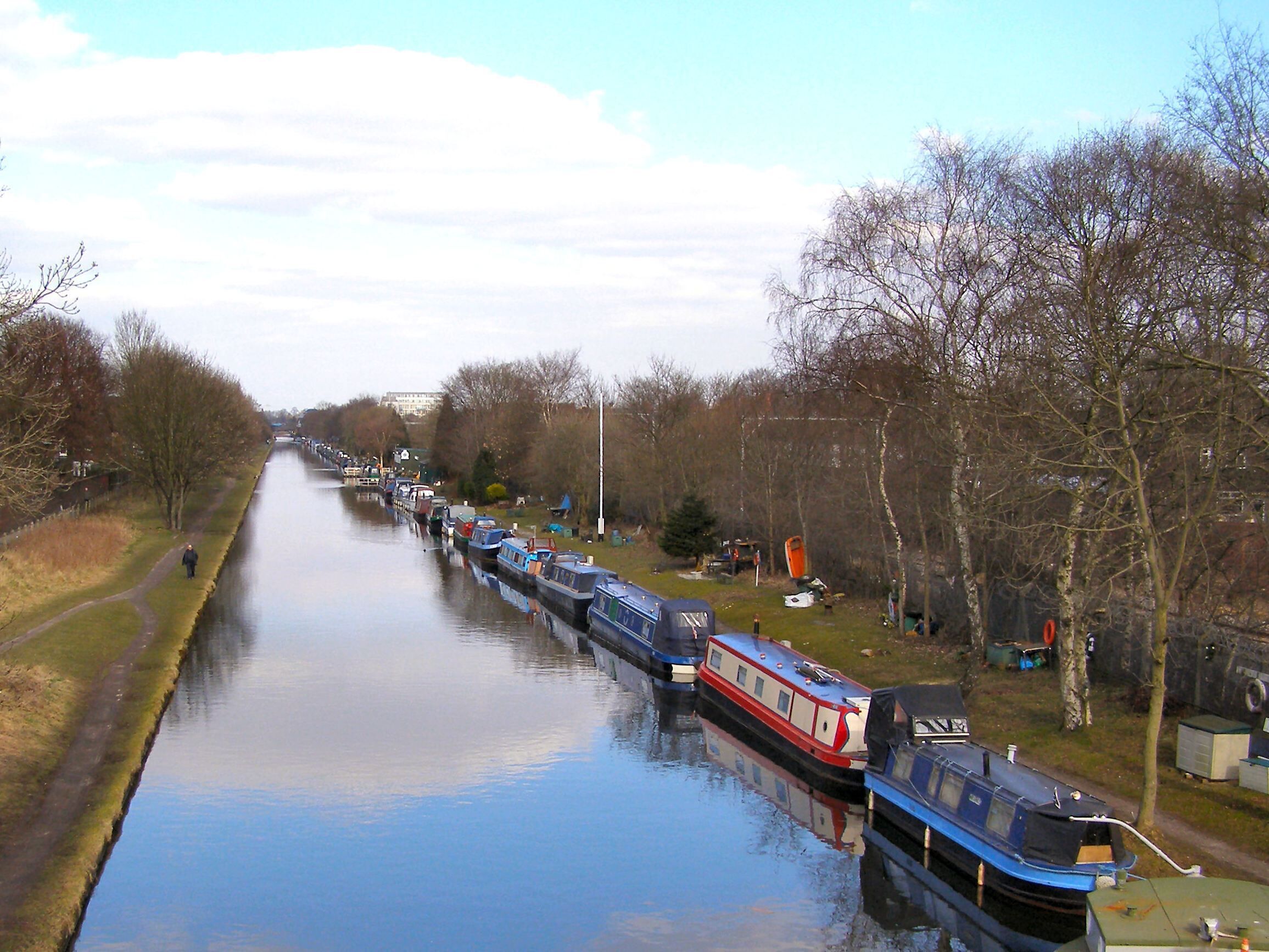 A canal lined with boats and trees.
